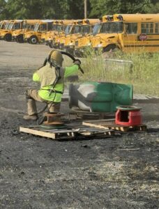 A worker sandblasting a large industrial part outdoors by Top Notch Sandblasting LLC in Randallstown, MD