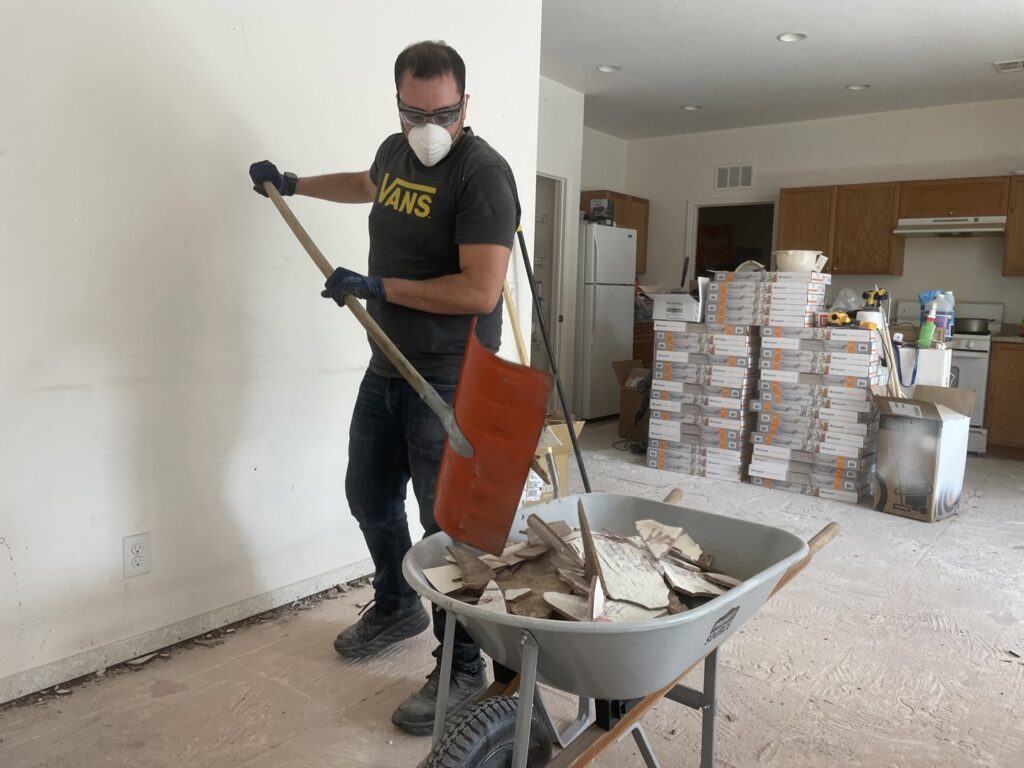 A Tidy Toss Las Vegas, NV worker shoveling broken tiles and debris into a wheelbarrow during a cleanout.