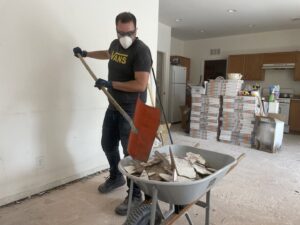 A Tidy Toss Las Vegas, NV worker shoveling broken tiles and debris into a wheelbarrow during a cleanout.