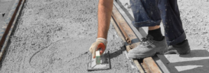 A worker using a trowel to smooth fresh concrete during a repair or installation project by American Mud Jack INC in Arvada, CO.