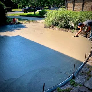 A worker smoothing freshly poured concrete for a new driveway installation by concrete poured & installed - cp&i in Buffalo, NY.