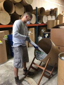 A worker sorting fluorescent tubes into a recycling drum for Quick Light Recycling in South San Francisco, CA.
