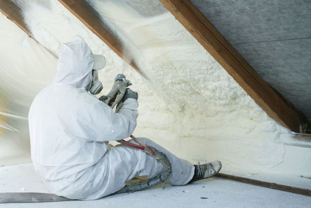 A worker spraying foam insulation in an attic, a service provided by Tito's Home Improvement LLC in Stamford, CT.