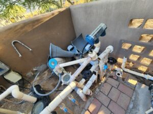 A worker spraying a new surface onto an empty pool, a service provided by Aqua Squad Pools & Landscaping in Gilbert, AZ.