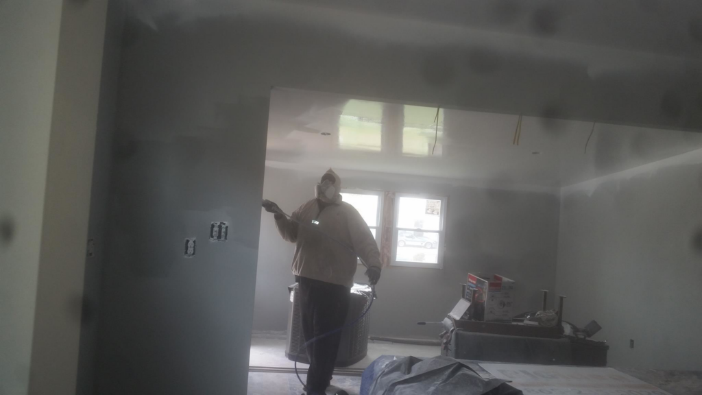 A worker in protective gear spraying primer on new drywall during a renovation project by Big Idea Construction, LLC in Knoxville, TN.