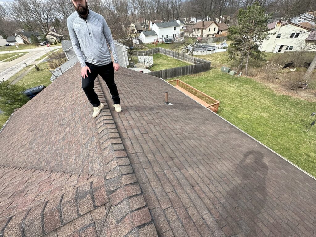 A SHIFT Roofing & Exteriors worker standing on a residential roof, likely for inspection, in Gahanna, OH