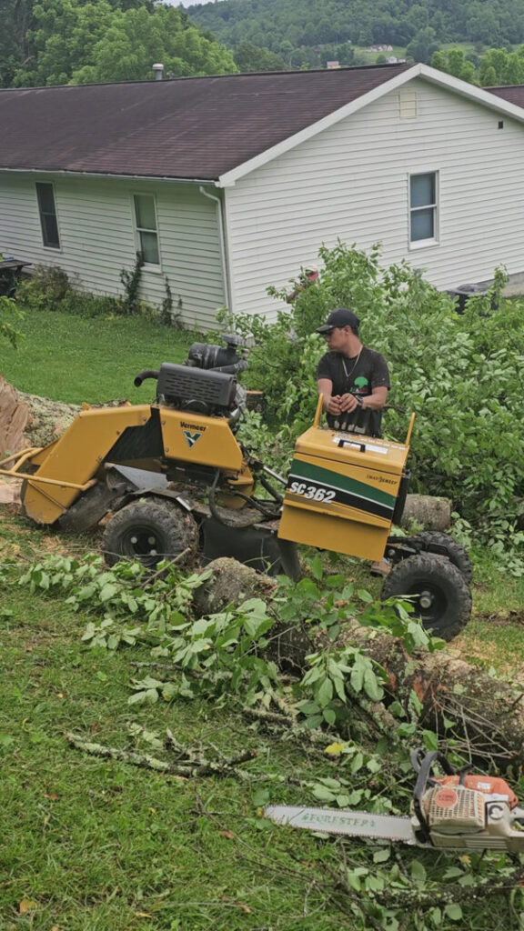 A worker operating a stump grinder with a chainsaw nearby, provided by Juarez Tree Service in Bawcomville, LA.