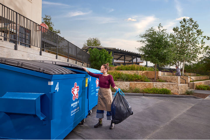 A worker sweeping cardboard waste on the floor of a recycling facility, illustrating waste management operations related to junk removal in Meridian, ID.