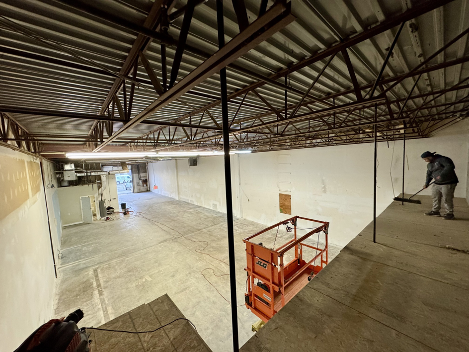 A worker sweeping the floor of a commercial space during renovation, showcasing handyman services by Potomac Exteriors LLC in Alexandria, VA.