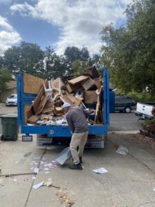 A worker sweeping up small debris from a driveway after a junk removal job by Junk Away & Cleaning in Sacramento, CA.