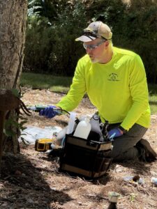 A worker performing tree health treatment by injecting nutrients into the base of a tree for All Wood's Tree Service in Ogden, UT.