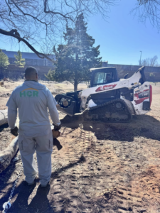 A worker from HCR, Inc. with a Bobcat skid-steer loader on a site preparation job in Boerne, TX.
