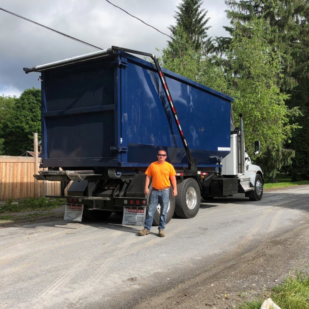 An Expert Dumpster team member standing next to a roll-off dumpster truck, ready for junk removal in Rochester, NY.