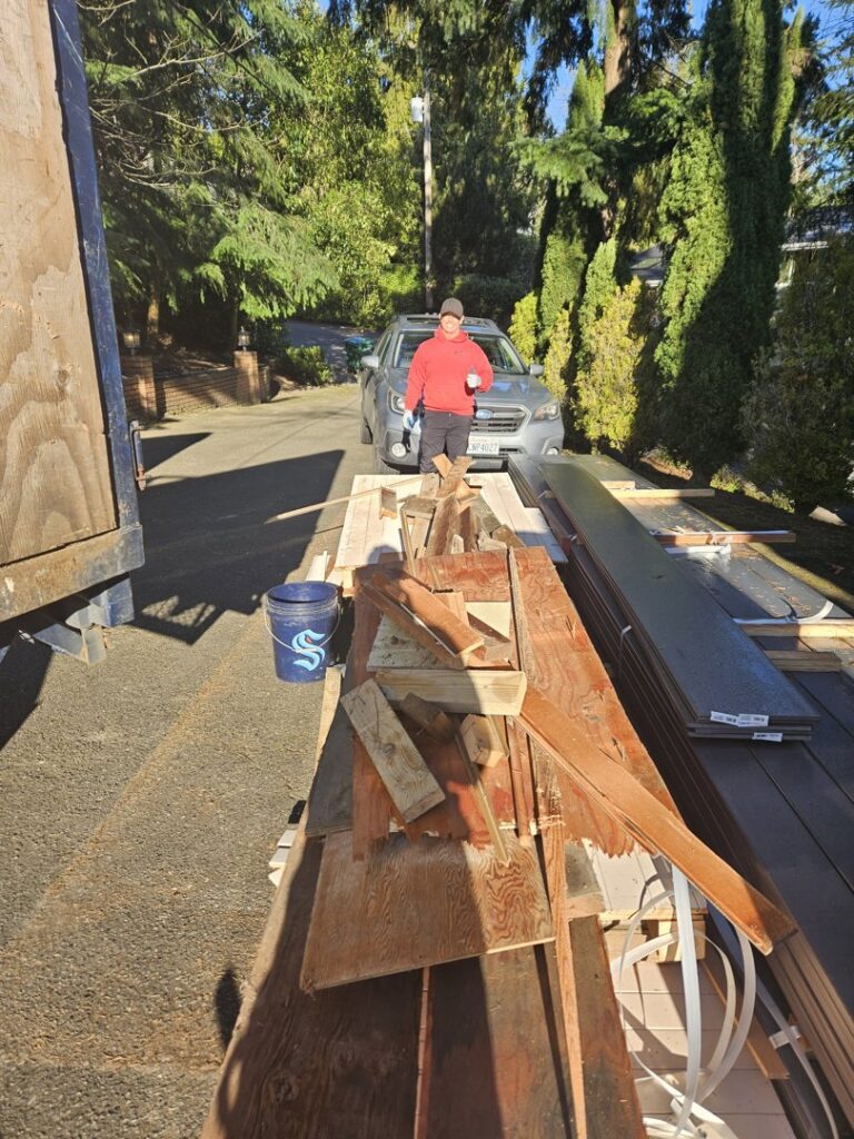 A Junkzilla Inc. worker standing next to a large pile of wood and construction debris for removal in Everett, WA.