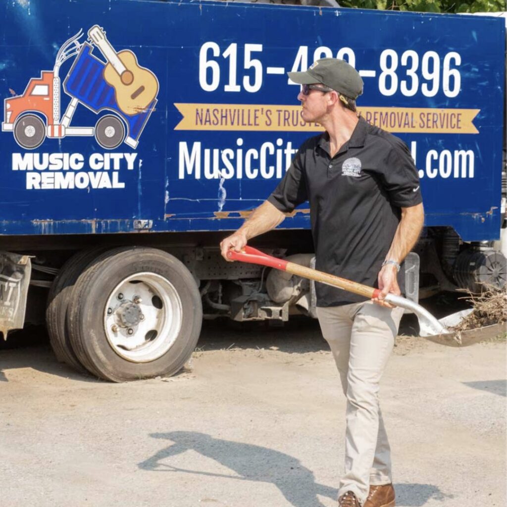 A Music City Removal worker holding a shovel in front of a branded junk removal truck in Nashville, TN.