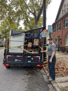A worker standing next to a trailer full of various junk items for removal by Junk Runner, LLC in East Berlin, PA.