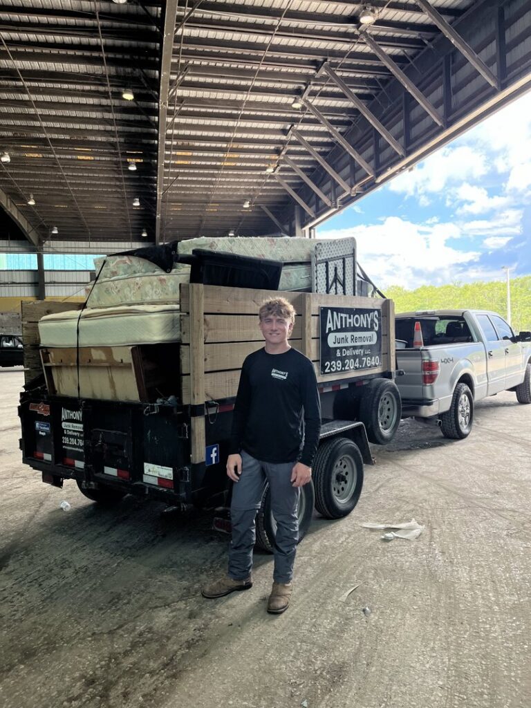 A worker standing in front of a dump trailer filled with mattresses and other junk for Anthony's Junk Removal & Delivery LLC in Cape Coral, FL.