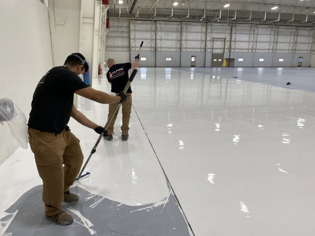 Workers applying a durable floor coating in an industrial facility by Alpine Painting and Sandblasting Contractors in Paterson, NJ.