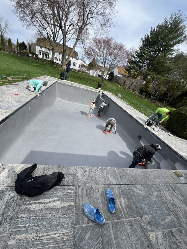 Workers applying a new finish to the interior of an empty swimming pool by B-rod Pool Service LLC in Norwalk, CT.