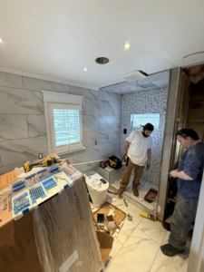 Two workers performing a bathroom renovation, installing tiles and fixtures for D&J's Construction Services LLC in Denver, CO.