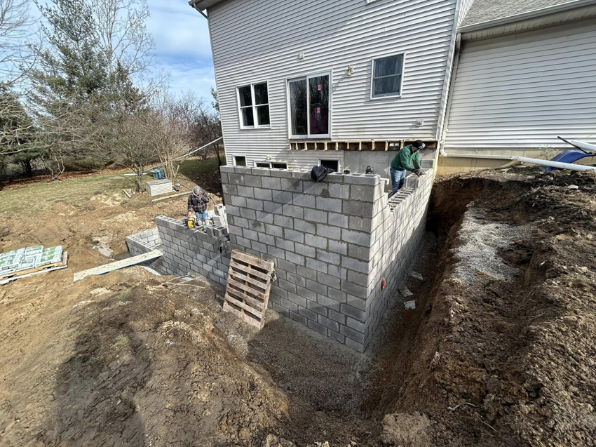 Workers constructing a new house foundation with concrete blocks for Steve Way Builders, LLC in Lansing, MI