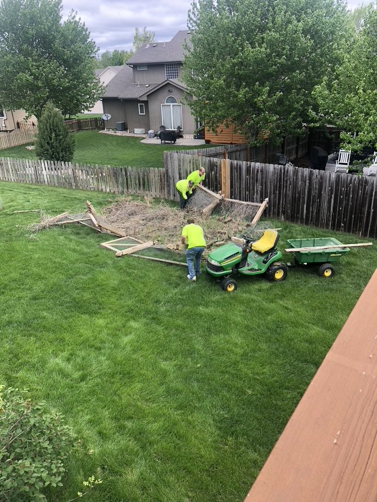 Two workers clearing yard debris and an old fence from a backyard for A1 Junk Removal Of Tucson, AZ.