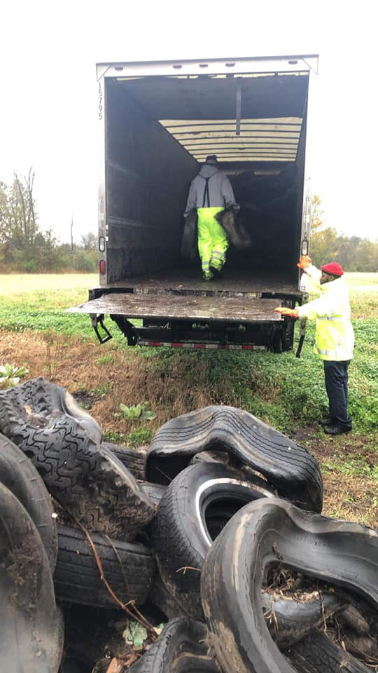 Workers collecting and loading a pile of old tires onto a truck for Environmental Rubber Recycling in Flint, MI.