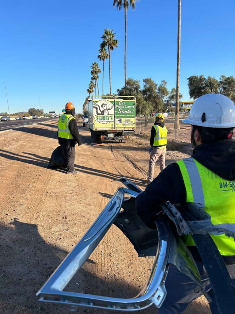 Skunky's Junk Removal workers collecting roadside debris with their truck in the background in Tempe, AZ.