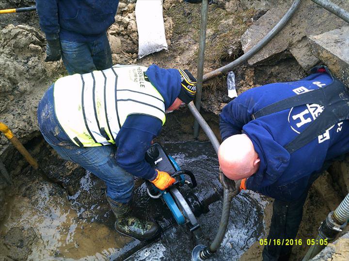 Two workers cutting pipes in a trench during a plumbing project for Hessville Plumbing in Hammond, IN.