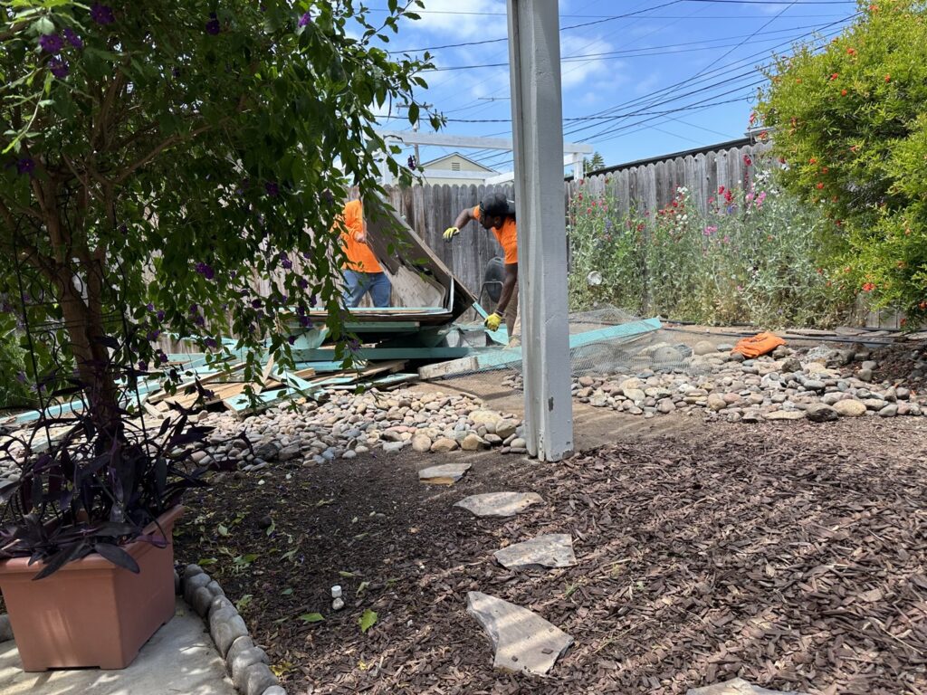 Workers from Impact Environmental Co. demolishing an old structure in a backyard in El Cajon, CA.