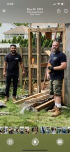 Two Junkin Irishman workers standing in front of a partially demolished wooden structure in Wayne, NJ, during a removal job.