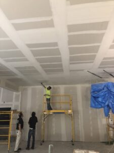 Workers on scaffolding finishing a drywall ceiling by Farnsworth Interiors Drywall and Plaster in Akron, OH