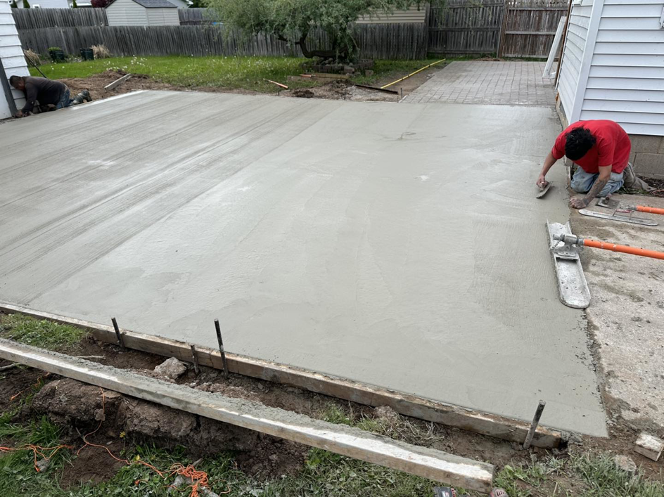 Workers using a float tool to smooth a new concrete slab by R&A Concrete Home Solutions LLC in Appleton, WI.