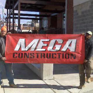Two workers proudly holding a Mega Construction banner at a job site in Philadelphia, PA.