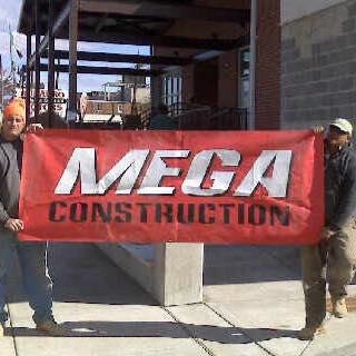 Two workers proudly holding a Mega Construction banner at a job site in Philadelphia, PA.