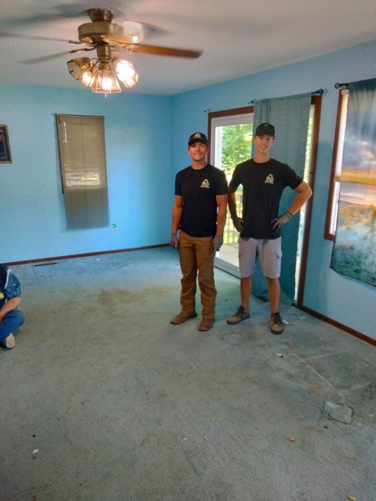 Two KJ Haul Away Junk Removal workers standing in a newly cleared room after completing a junk removal job in Cedar Rapids, IA.