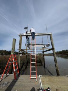Workers installing a boat lift and dock structure over water for Coastal Dock and Resurfacing in Beaufort, SC.