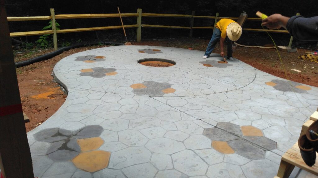 Workers installing a decorative concrete patio with a central fire pit area for Rodriguez Concrete Creations in Rock Hill, SC.
