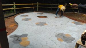 Workers installing a decorative concrete patio with a central fire pit area for Rodriguez Concrete Creations in Rock Hill, SC.