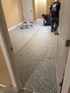 Workers installing speckled epoxy flooring in a room, a service provided by Mp painting and roofing LLC in Dayton, OH