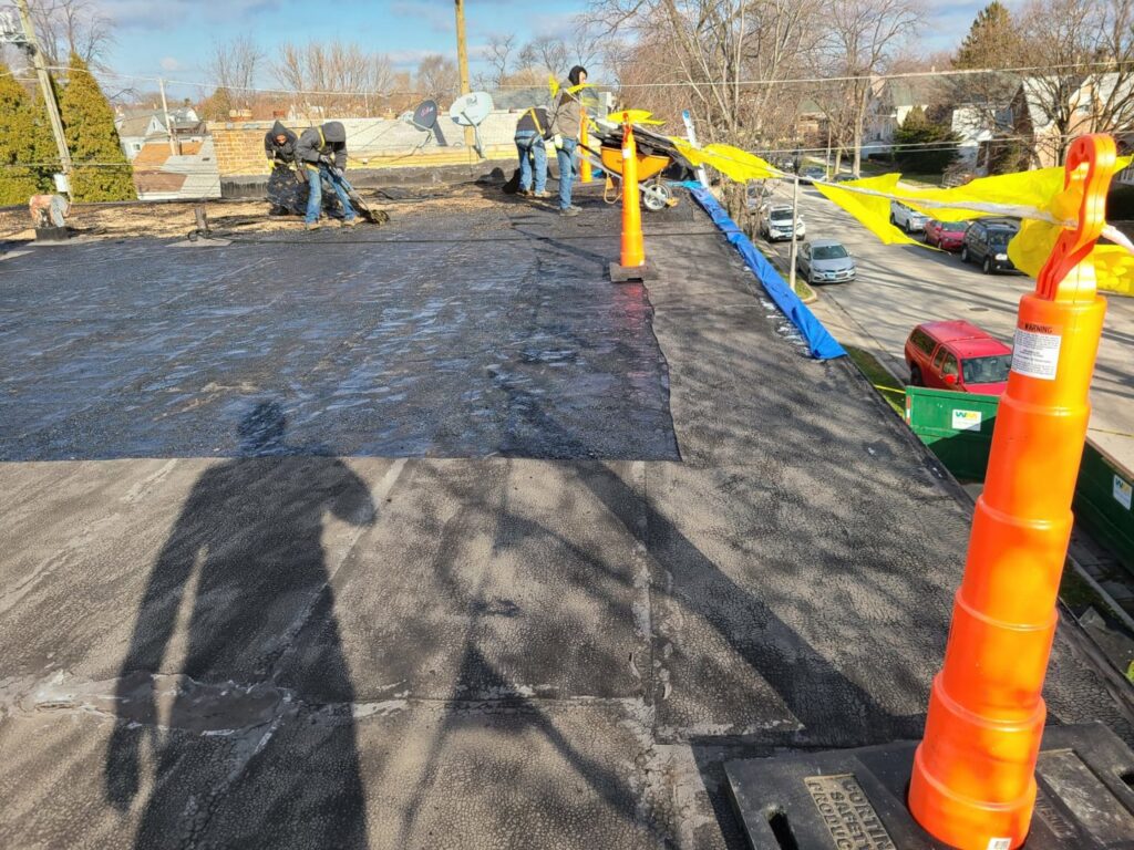 Workers installing new flat roofing material on a commercial building for Pro DK Contractor LLC in Chicago, IL.