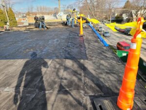 Workers installing new flat roofing material on a commercial building for Pro DK Contractor LLC in Chicago, IL.