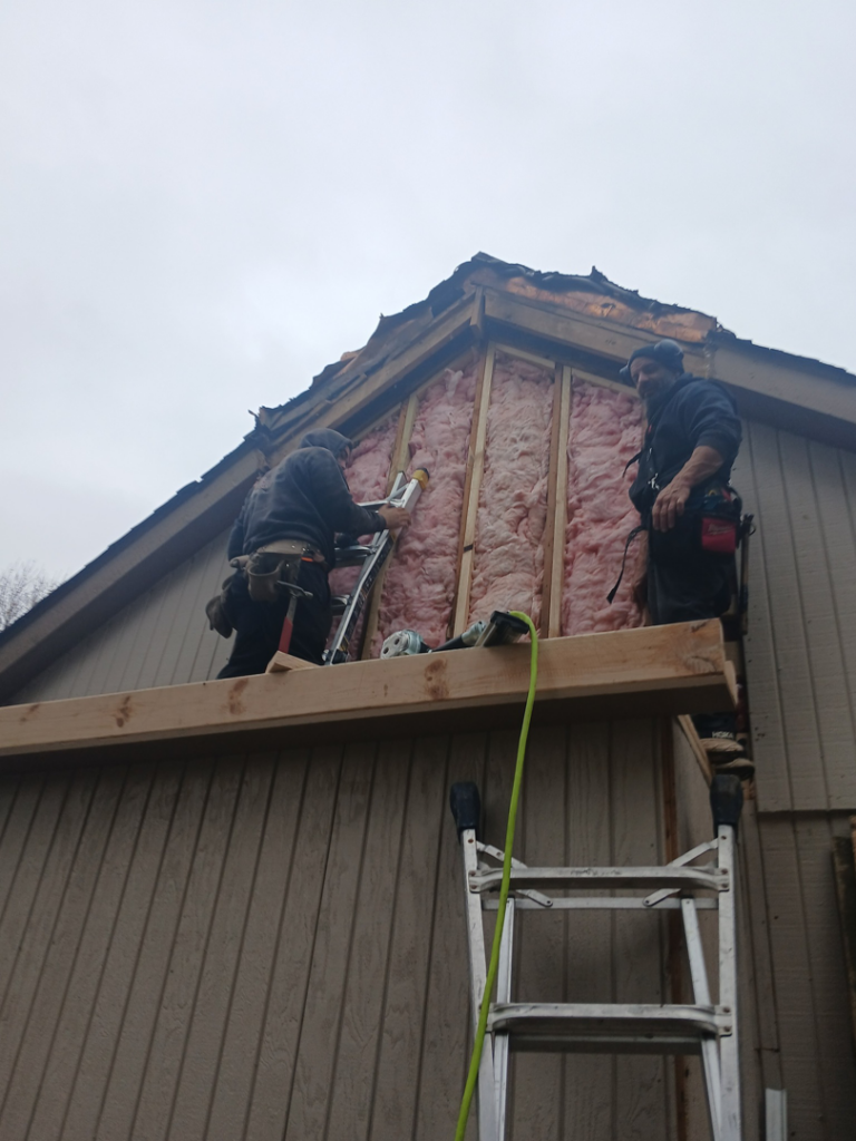 Two workers installing insulation and siding on a house by Exterior Renovations, LLC in Clinton Township, MI.
