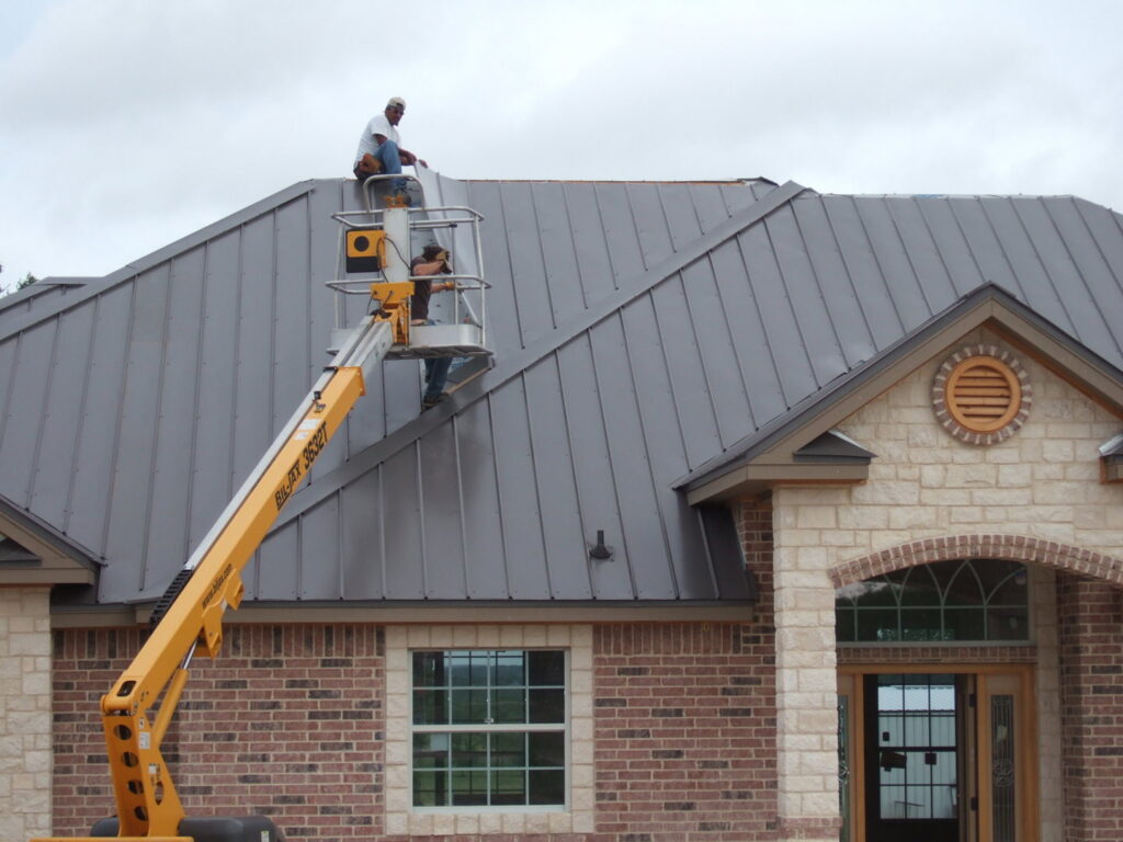 Workers installing a new metal roof on a residential house, showcasing work by Austin Roofing and Construction in Austin, TX.