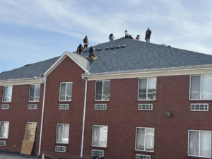Workers installing a new shingle roof on a commercial building for Elegant Home Exteriors in Flourance, KY.