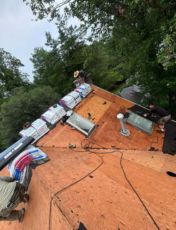 Workers installing new roof shingles and skylights on a residential home for Goldstone Contracting Inc. in Gambrills, MD.