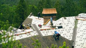 Workers installing new roof shingles on a house, showcasing Proline Roofing's work in Shipshewana, IN.