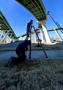 Two workers installing or repairing poles under a bridge, showcasing handyman services by Memphis Fence Company, LLC in Memphis, TN.