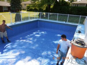 Two workers installing a new pool liner inside an inground pool, demonstrating services by My Pool Guys of Erie, PA.