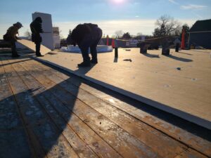 Construction workers installing roof insulation on a flat roof for Pro DK Contractor LLC in Chicago, IL.